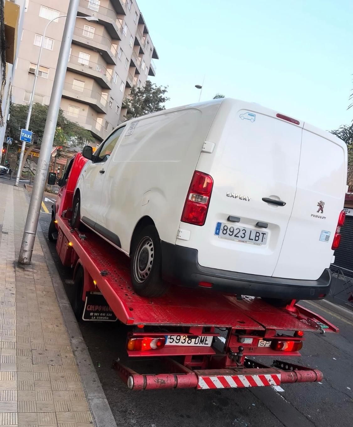 Una camioneta blanca está encima de una grúa roja