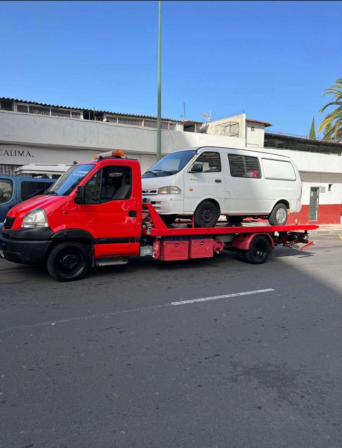 Una camioneta blanca está siendo remolcada por una grúa roja