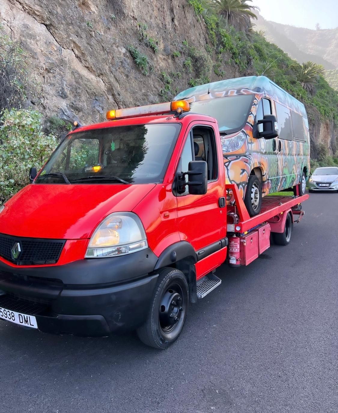 Una grúa roja transporta una furgoneta verde