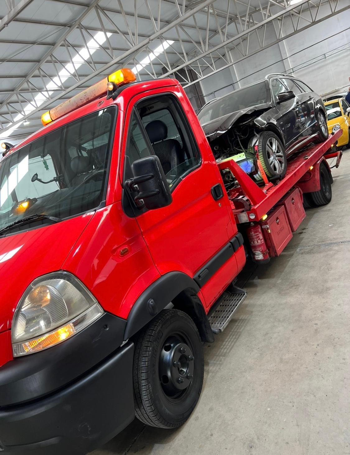 Una grúa roja con un coche en la parte trasera está estacionada en un garaje.