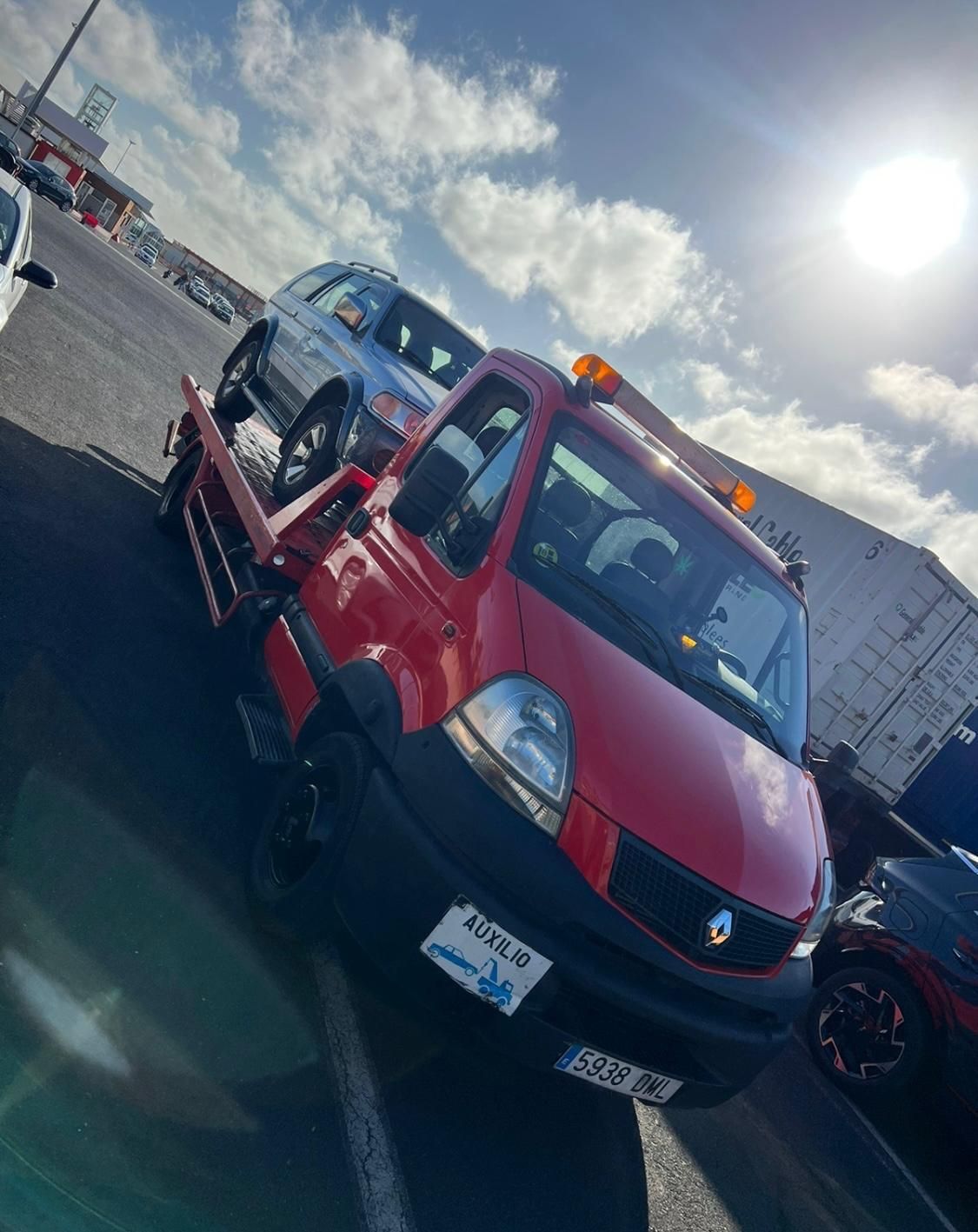 Una grúa roja transporta una camioneta plateada