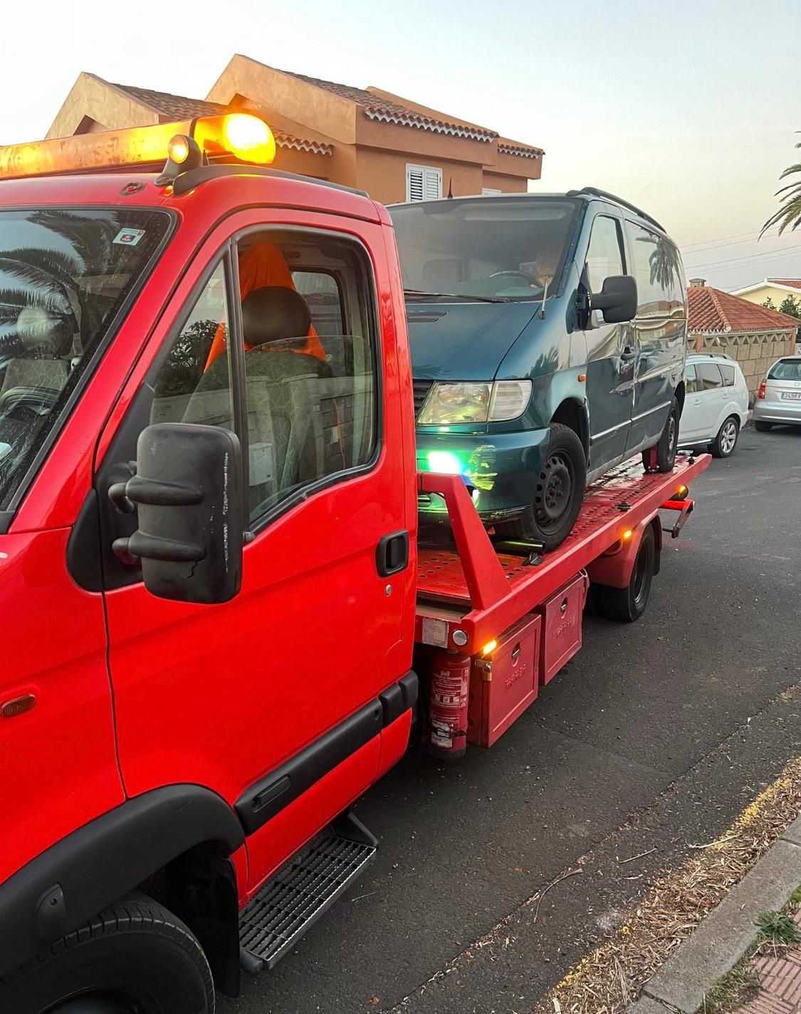 Una grúa roja transporta una furgoneta azul