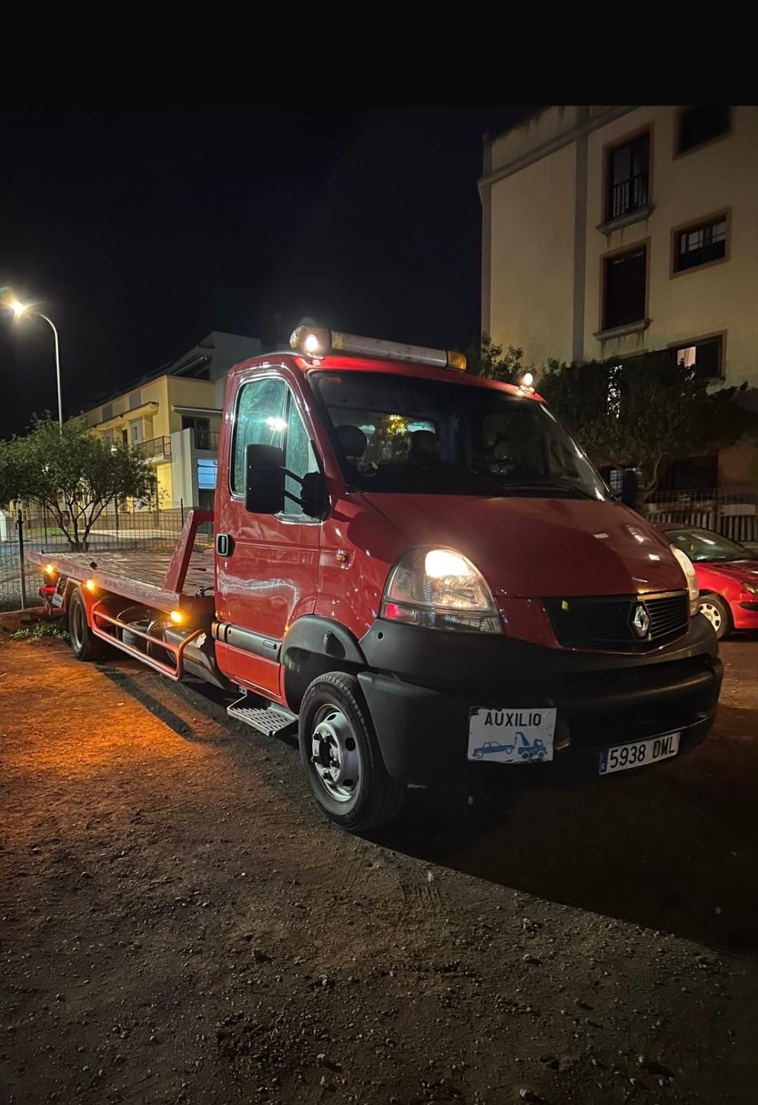 Una grúa roja está estacionada en un estacionamiento por la noche.