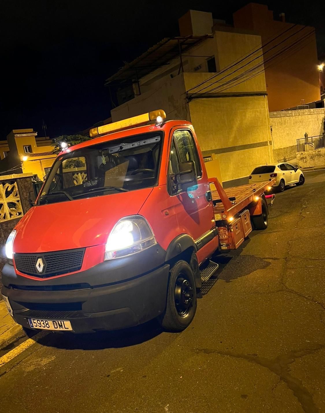 Una grúa roja está estacionada al costado de la carretera por la noche.