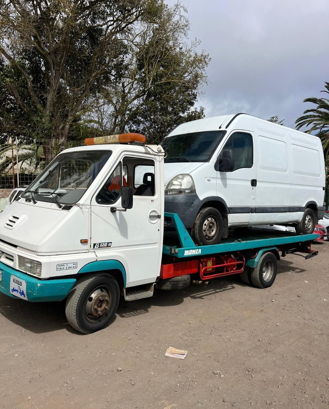 Una grúa está remolcando una camioneta blanca en un estacionamiento.