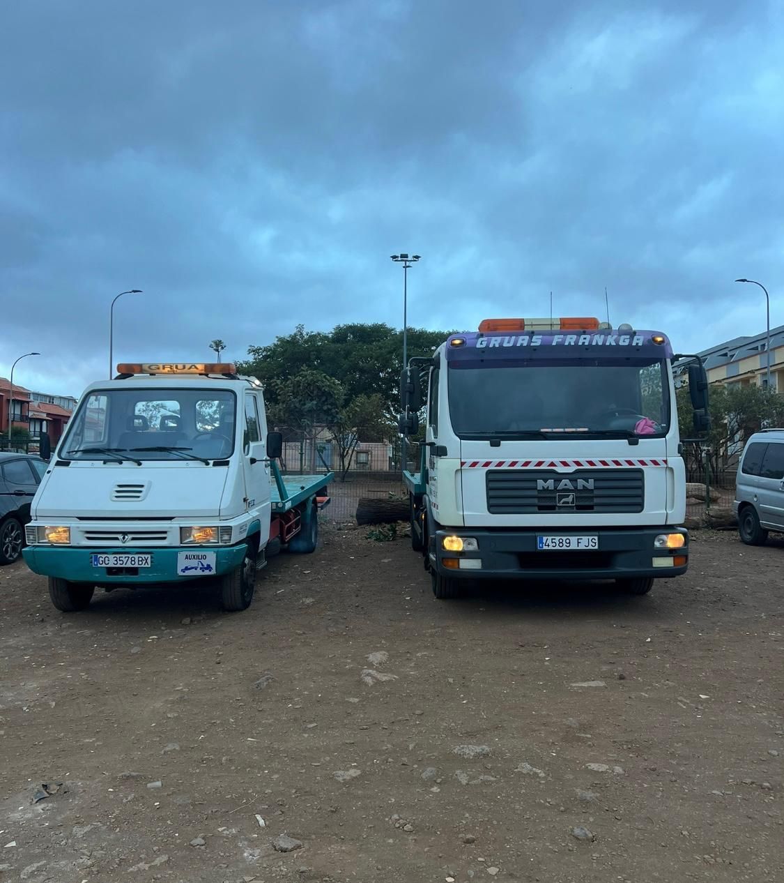 Dos grúas están estacionadas una al lado de la otra en un lote de tierra.