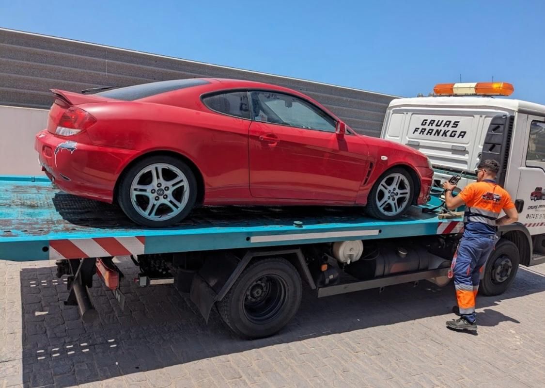Un coche rojo está siendo remolcado por una grúa.