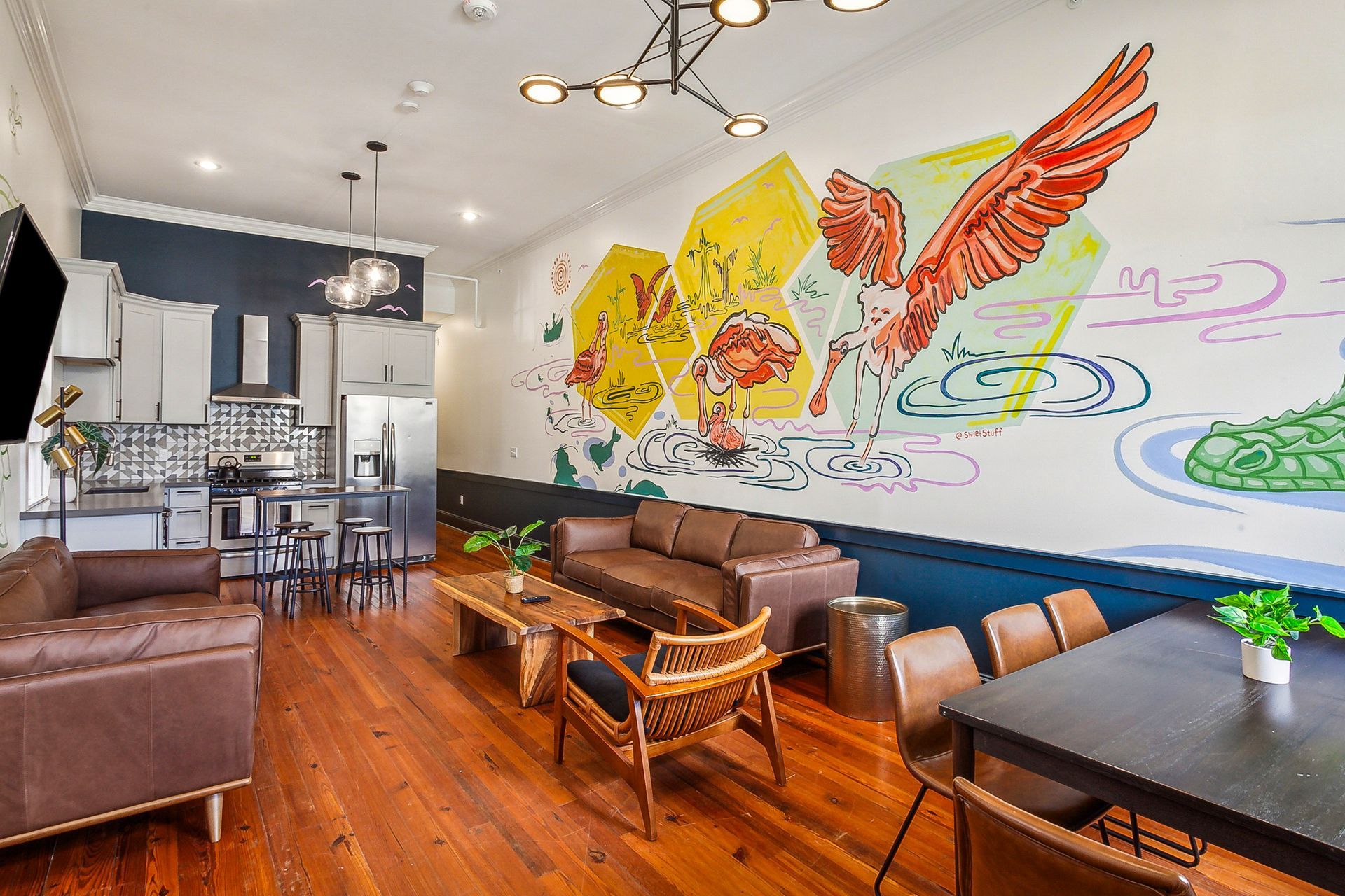 A living room with a couch , table , chairs and a mural on the wall.