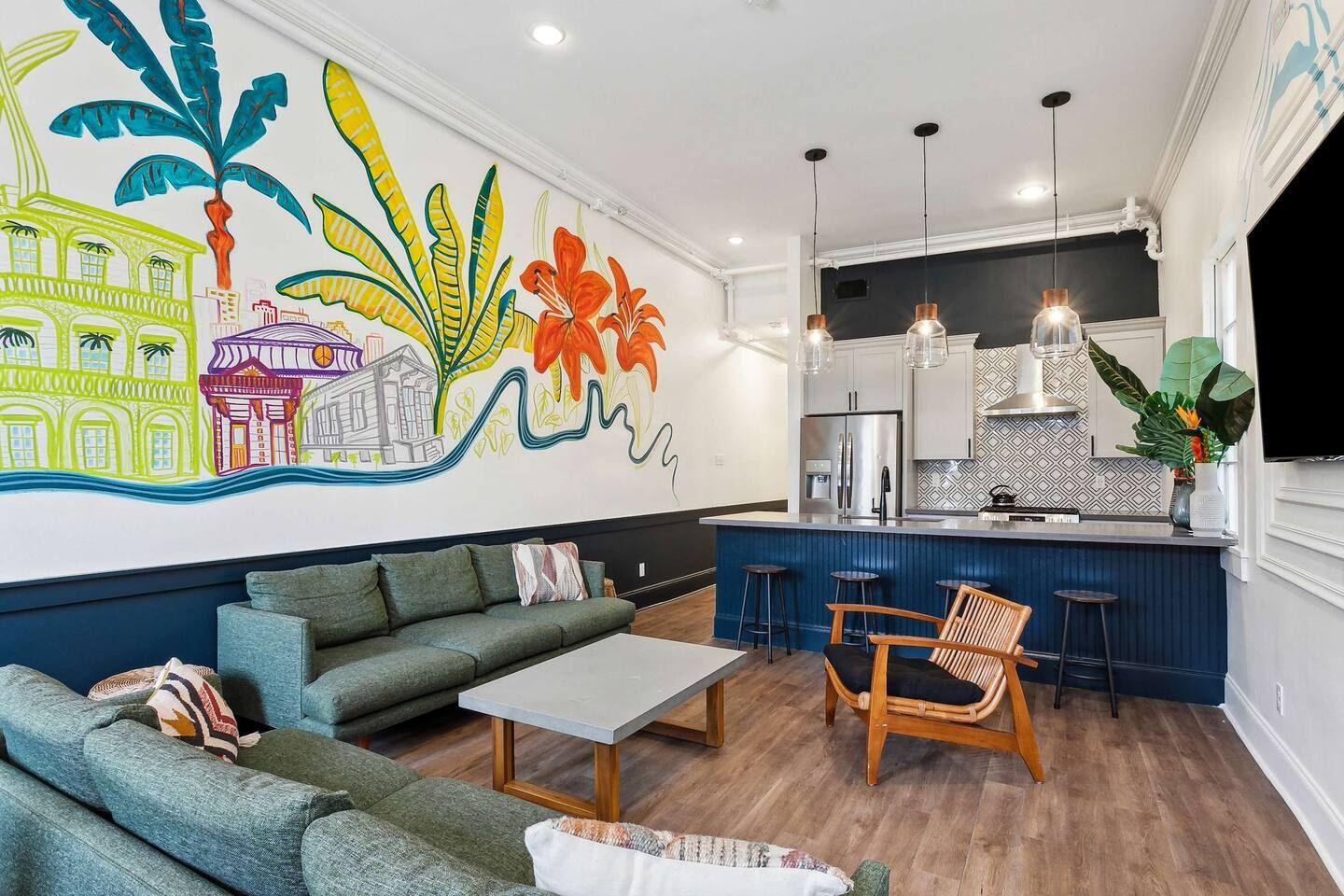 A living room with a couch , chairs , coffee table and a mural on the wall.