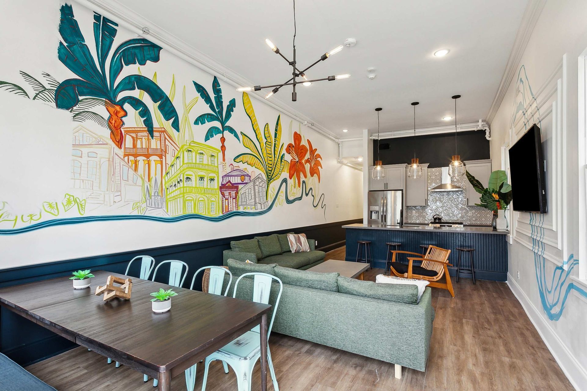 A living room with a couch , table , chairs and a mural on the wall.