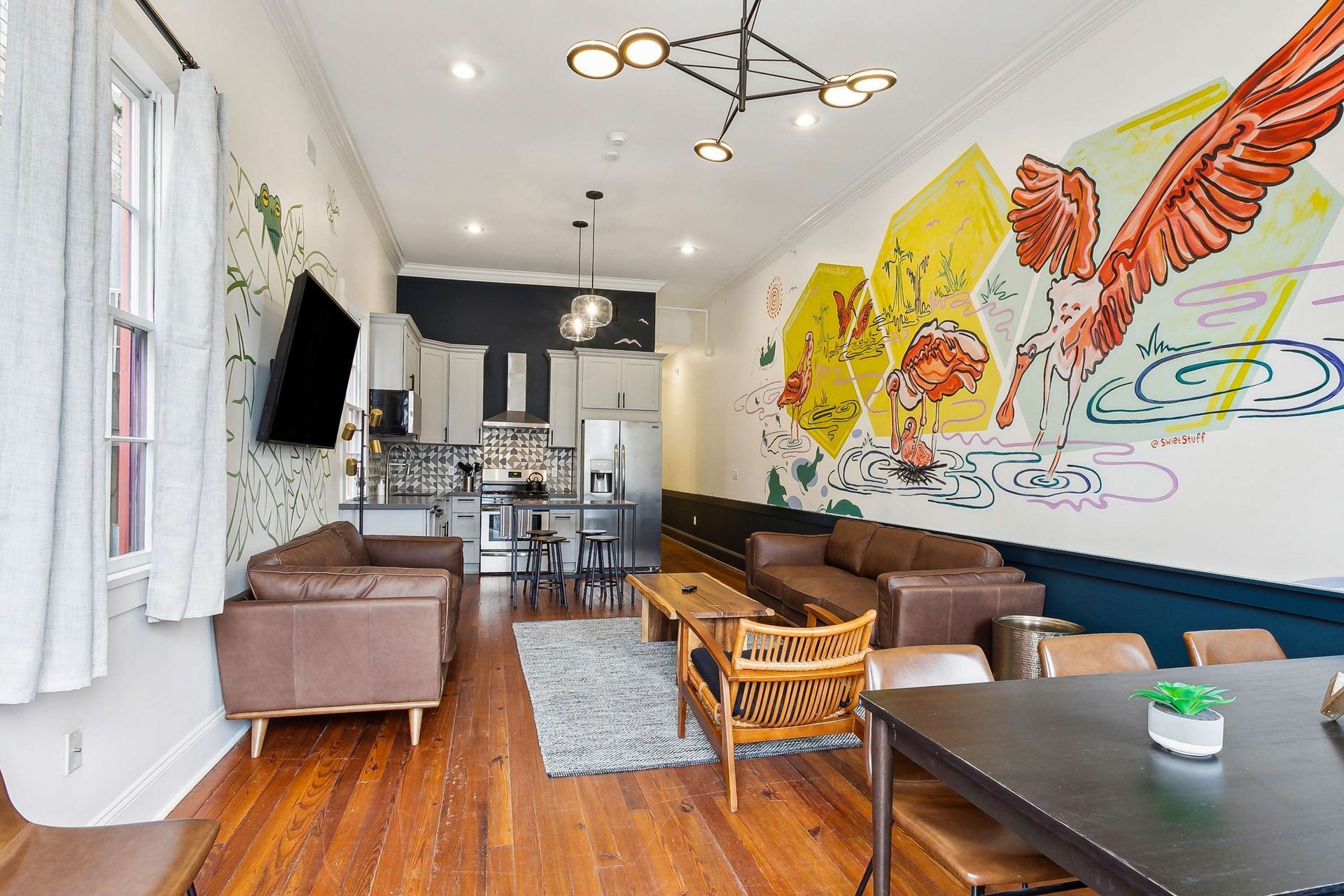 A living room with a couch , table , chairs and a mural on the wall.