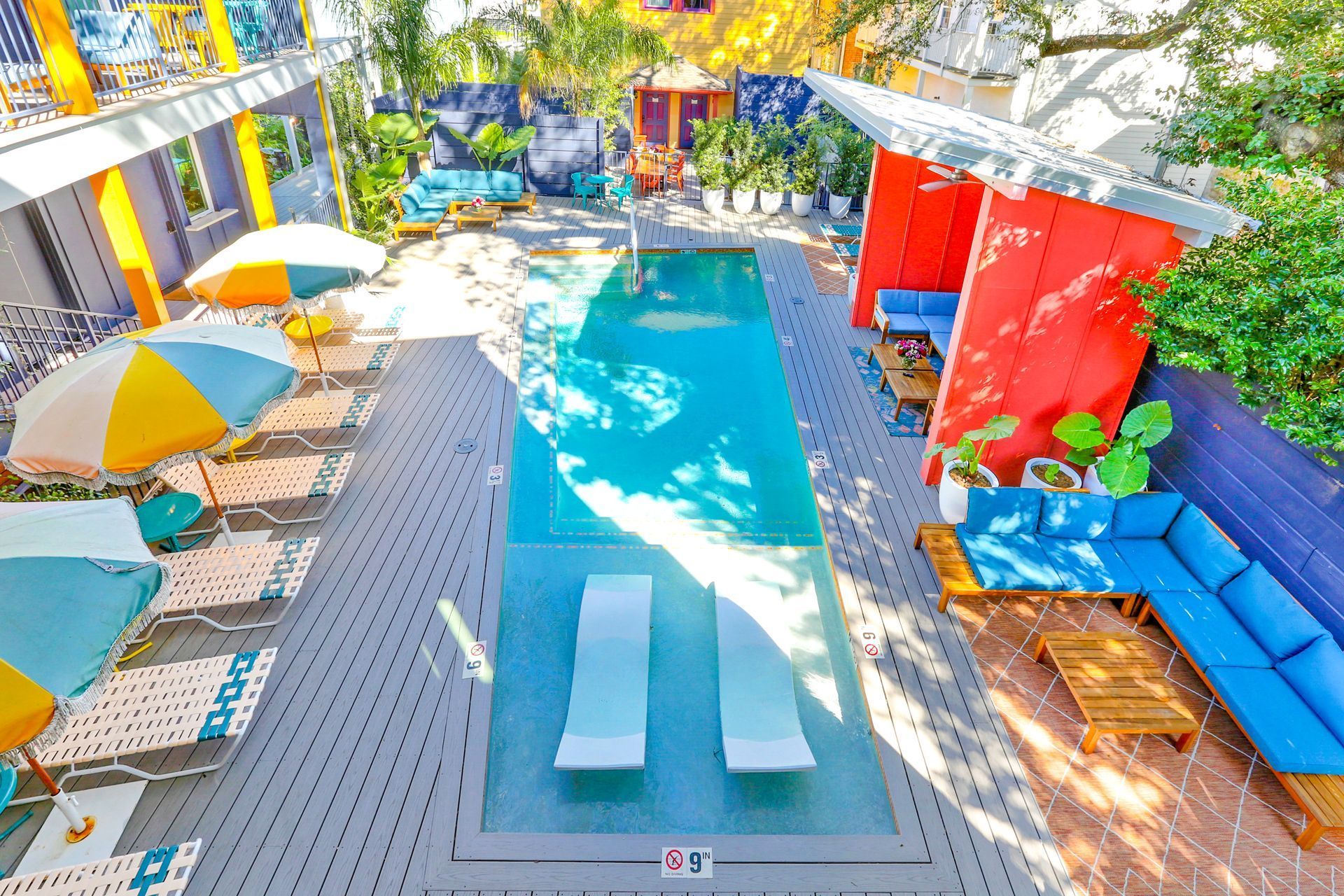 An aerial view of a swimming pool surrounded by chairs and umbrellas.