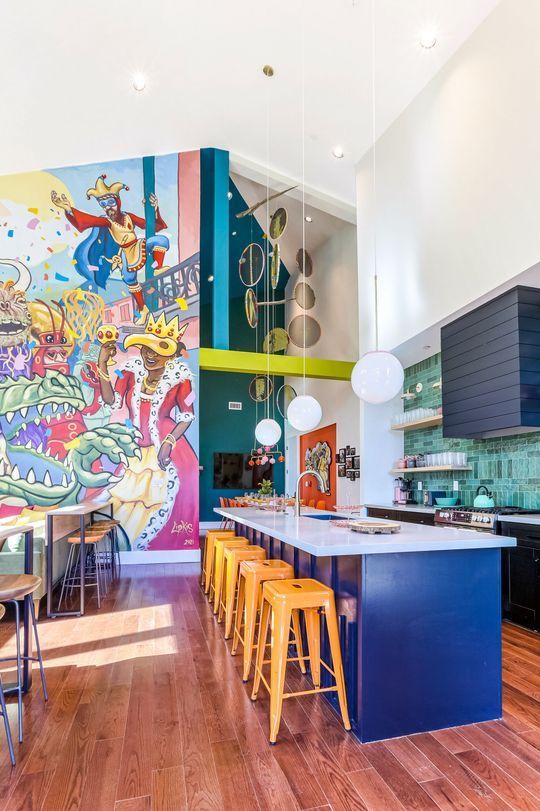 A kitchen with a large island and stools and a mural on the wall.
