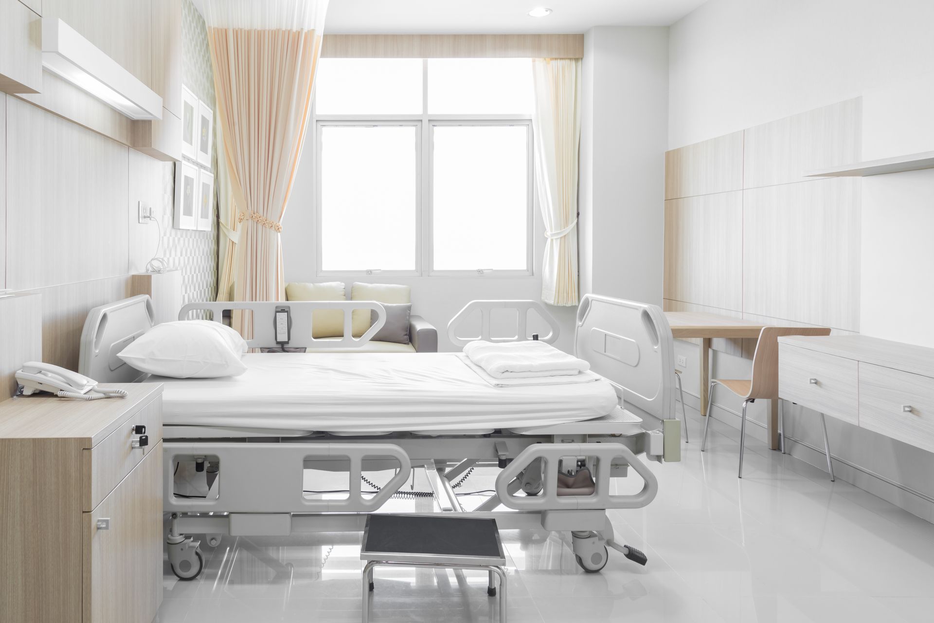 Chambre d'hôpital avec un lit, du matériel médical, une fenêtre et une petite table.