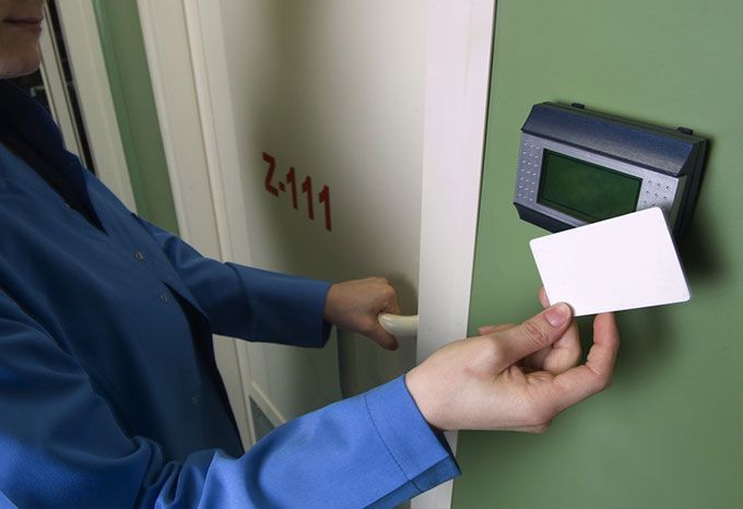 Personne utilisant une carte blanche pour déverrouiller une porte avec un lecteur de carte à clé numérique ; assise à l'intérieur.