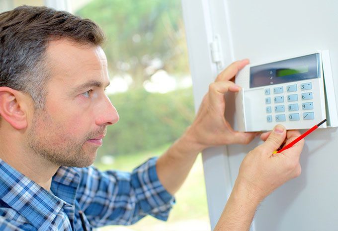 Un homme installe un clavier de système de sécurité sur un mur.