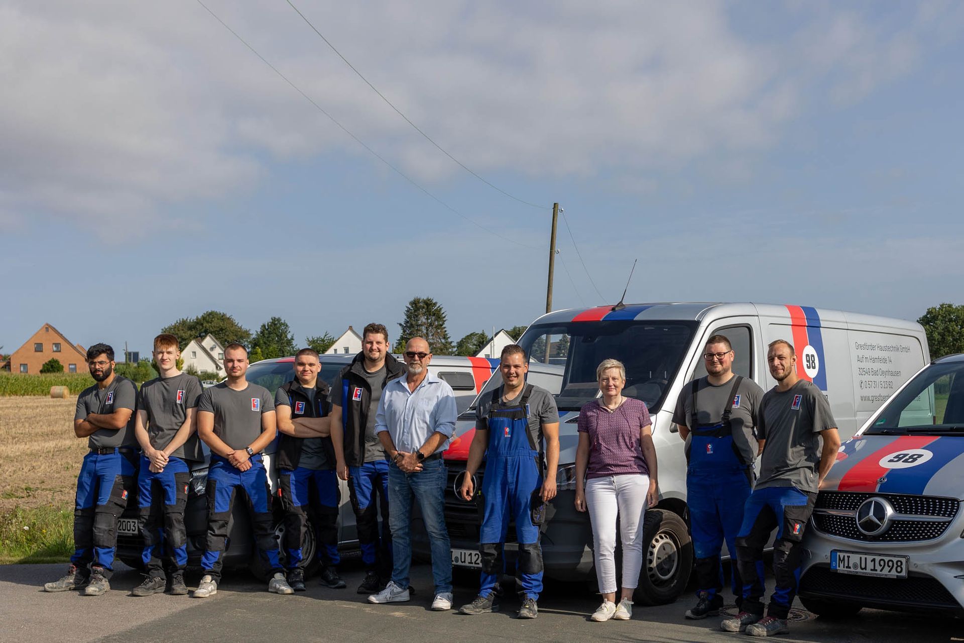 Eine Gruppe von Menschen posiert vor ihren Lieferwagen für ein Foto.