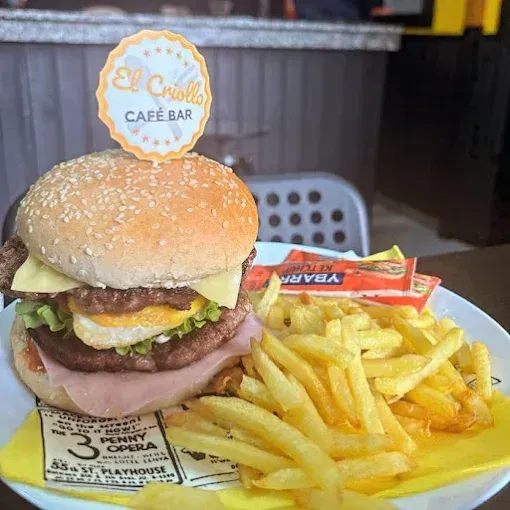 Una hamburguesa con huevo, jamón y papas fritas en un plato en El Criollo Café Bar.