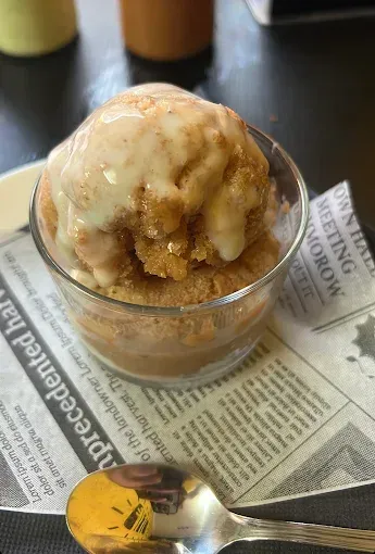 Postre en copa. Tarta crujiente con glaseado blanco y cobertura de canela, servida sobre papel de periódico.