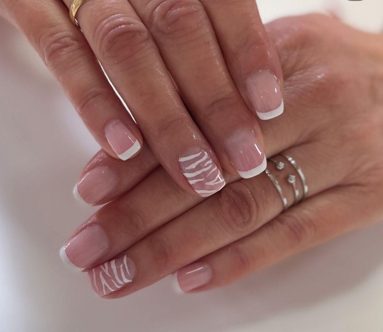 Manos con uñas de punta francesa, una de ellas con diseño en espiral blanco.