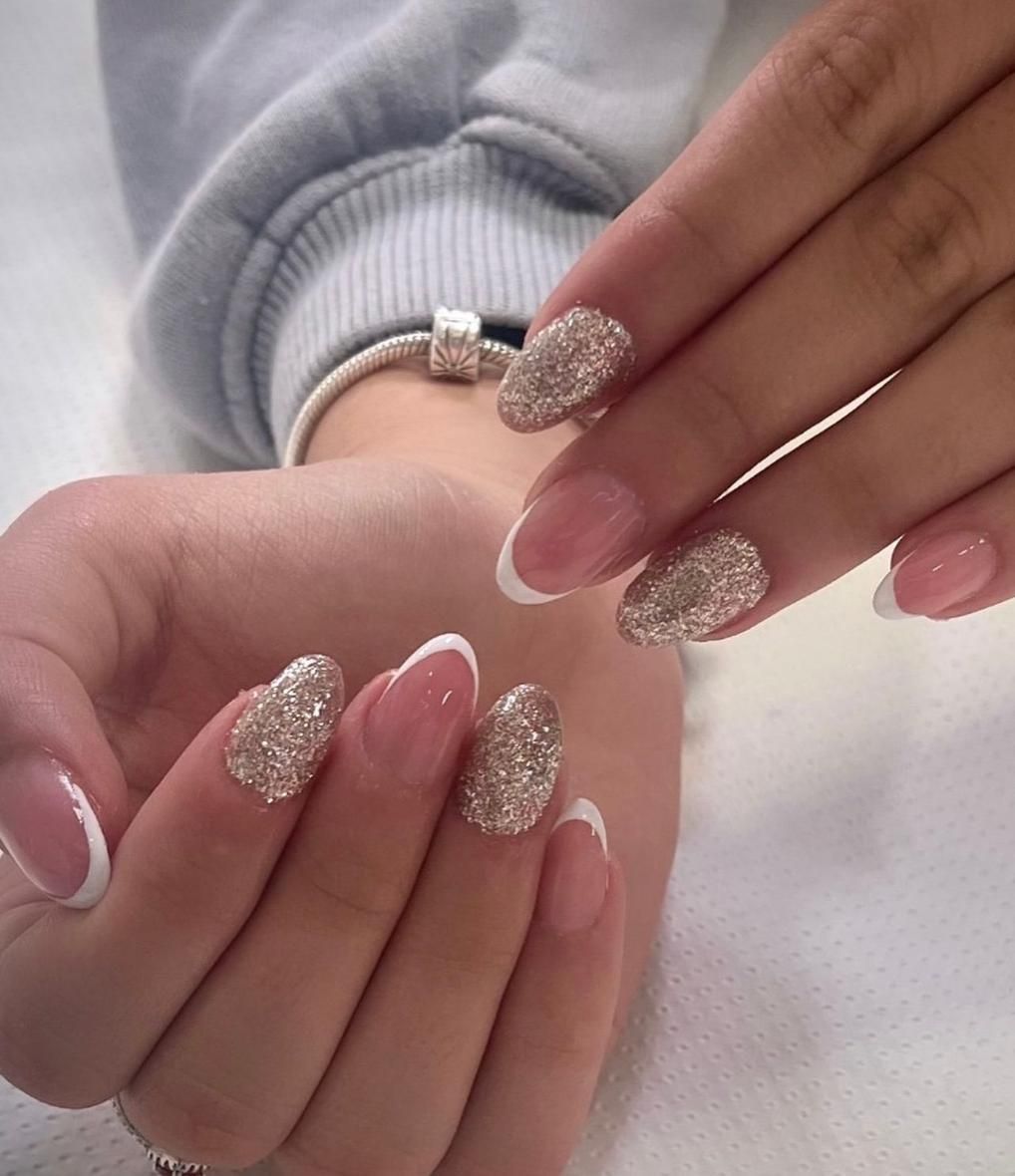 Manos con diseño de uñas con punta francesa y brillo.