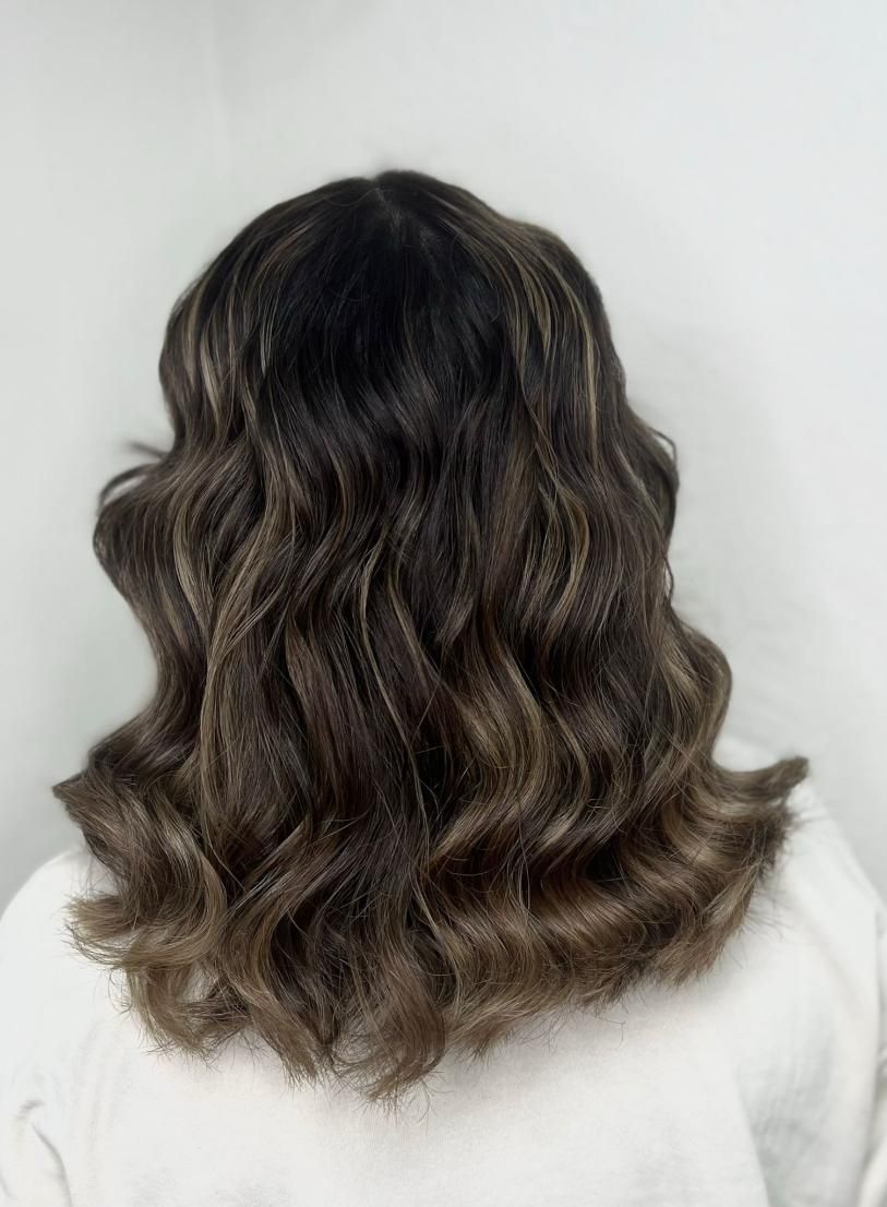 Cabello oscuro y ondulado, con reflejos castaños más claros, sobre fondo blanco.
