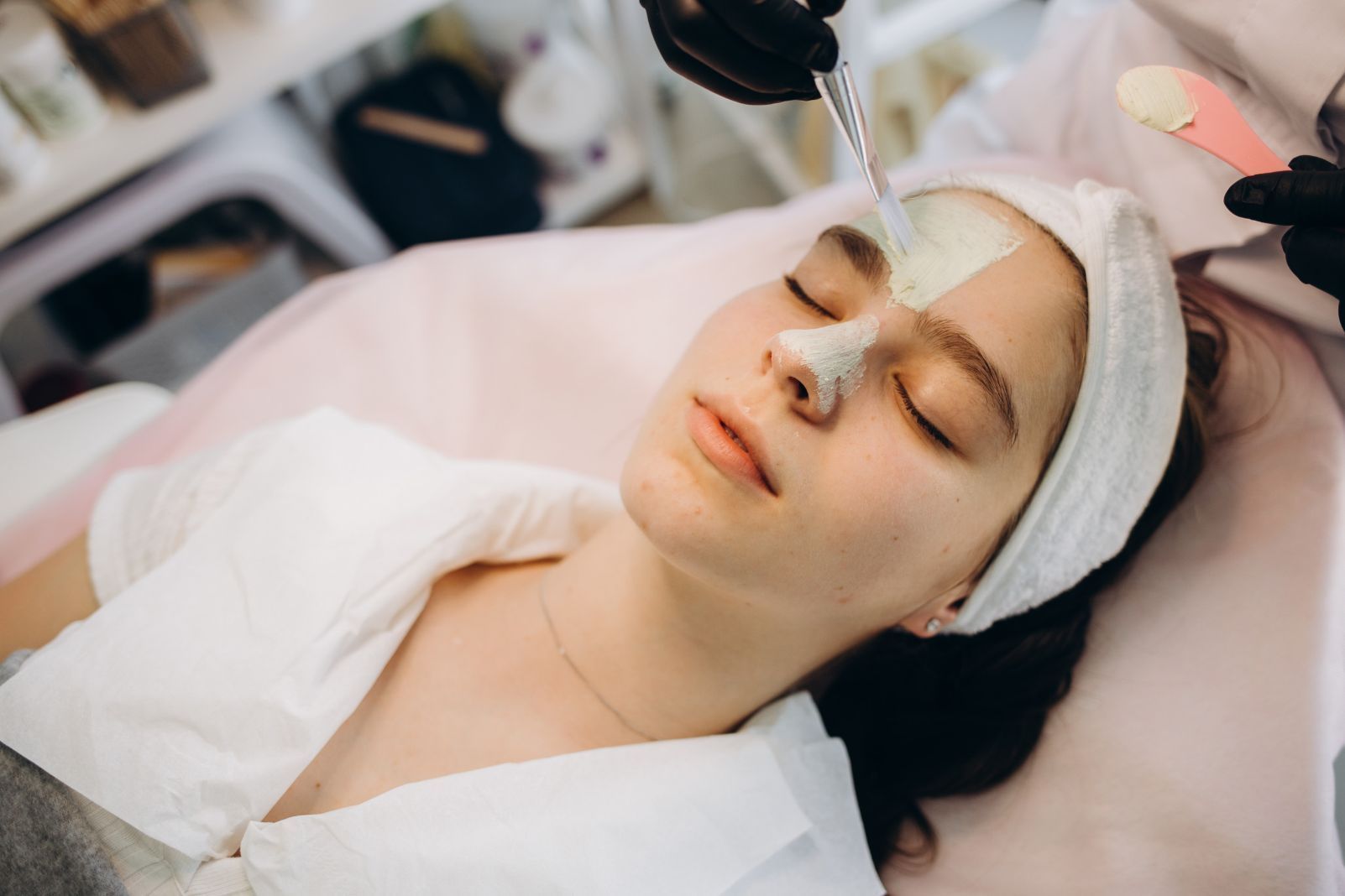 Persona recibiendo un tratamiento facial en un spa, con una mascarilla aplicada en la cara.