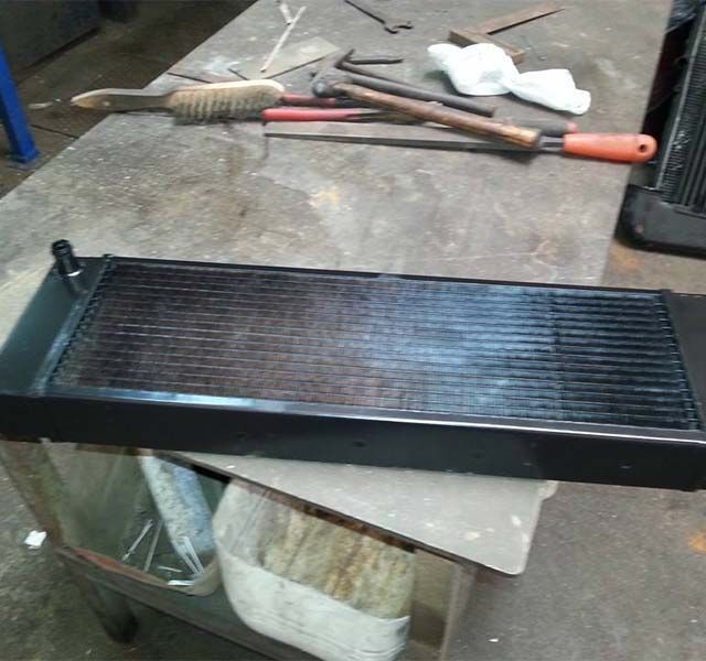 Un radiador negro está sobre una mesa junto a herramientas.