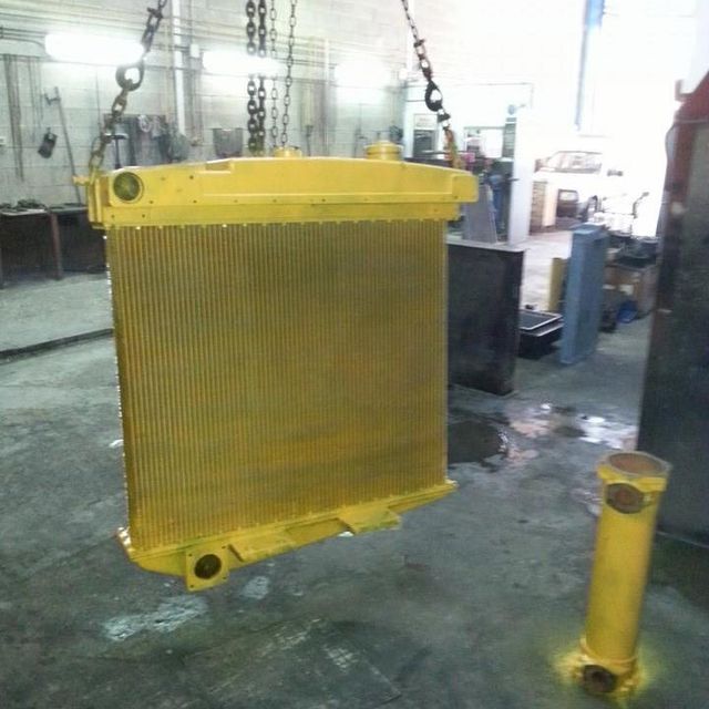 Un radiador amarillo cuelga de cadenas en un garaje.