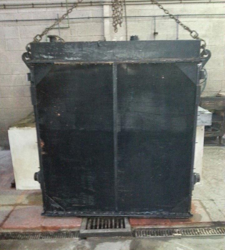 Un gran radiador negro cuelga de cadenas en una habitación.