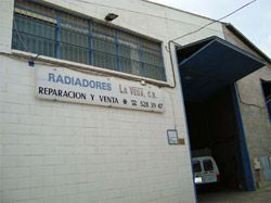 Un edificio blanco con un letrero al costado que dice ``radiadores la vega ca reparacion y venta''.