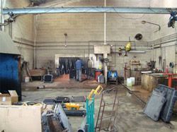 Un hombre está soldando una pieza de metal en una fábrica.