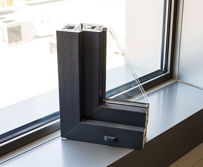 Partie d'un cadre de fenêtre gris foncé montrant plusieurs vitres sur un appui de fenêtre.