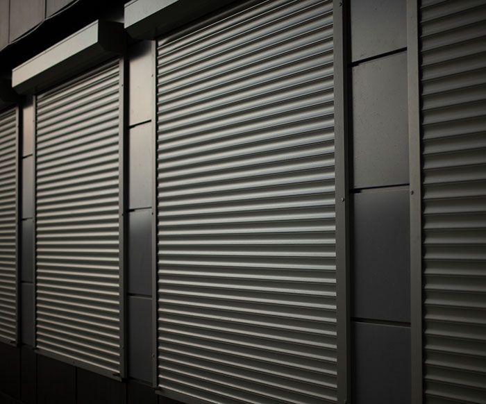 Volets de sécurité en métal gris sur la façade d'un bâtiment.