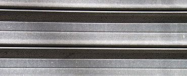 Gros plan sur une surface métallique présentant des rayures horizontales alternées gris clair et gris foncé.