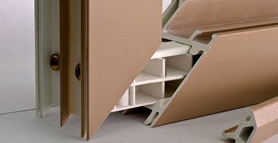 Gros plan sur une vue en coupe des composants d'un cadre de fenêtre beige et blanc, illustrant leur construction.