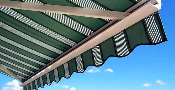 Un auvent à rayures vertes et blanches se détachant sur un ciel bleu éclatant.
