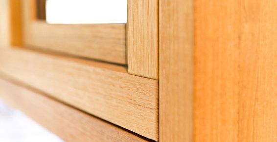 Gros plan sur un cadre en bois clair avec une petite découpe carrée, faisant partie d'un meuble ou d'un objet similaire.