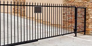 Portail en métal noir devant un mur de pierre.