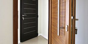 Deux portes en bois, l'une sombre et fermée, l'autre claire et entrouverte, dans un coin de la pièce.