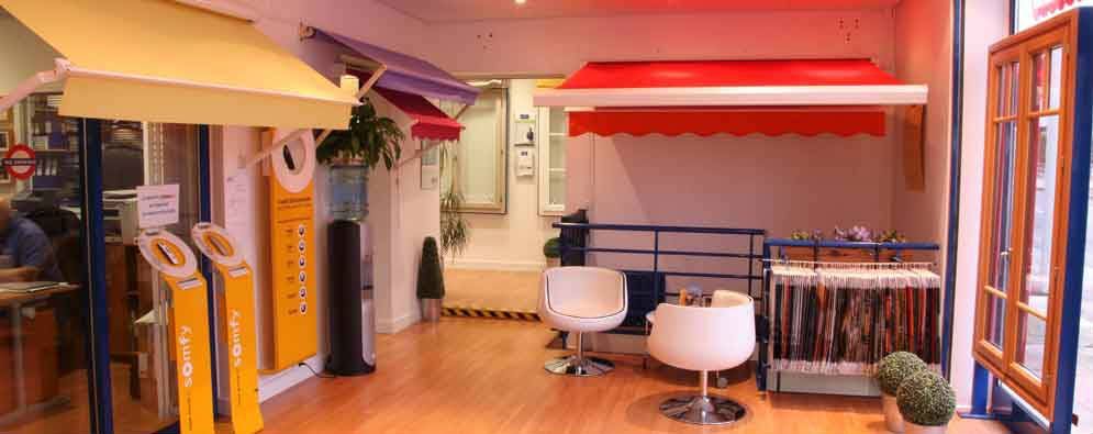 Intérieur d'un magasin présentant des auvents et des encadrements de fenêtres. On y voit différents styles d'auvents et deux chaises.