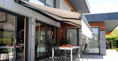 Terrasse avec store rétractable, table, chaises et maison moderne.