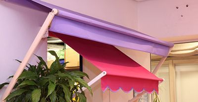 Auvent violet et rose au-dessus d'une fenêtre, avec un bord festonné et des supports de couleur claire.