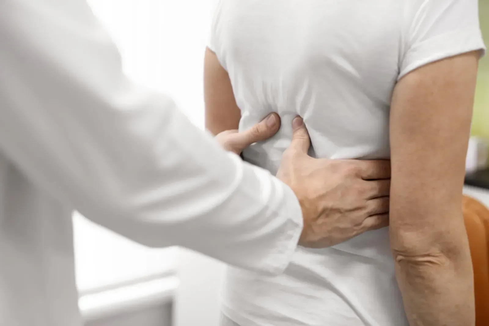 Una sala de exploración médica limpia y blanca con una camilla central