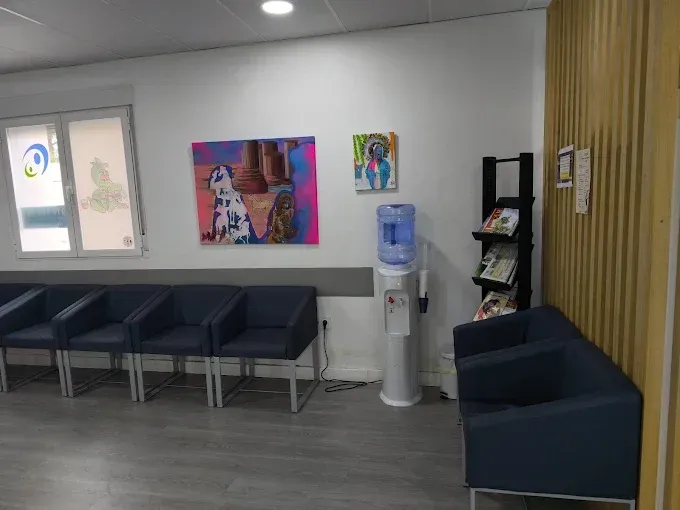 Una sala de exploración médica limpia y blanca con una camilla central