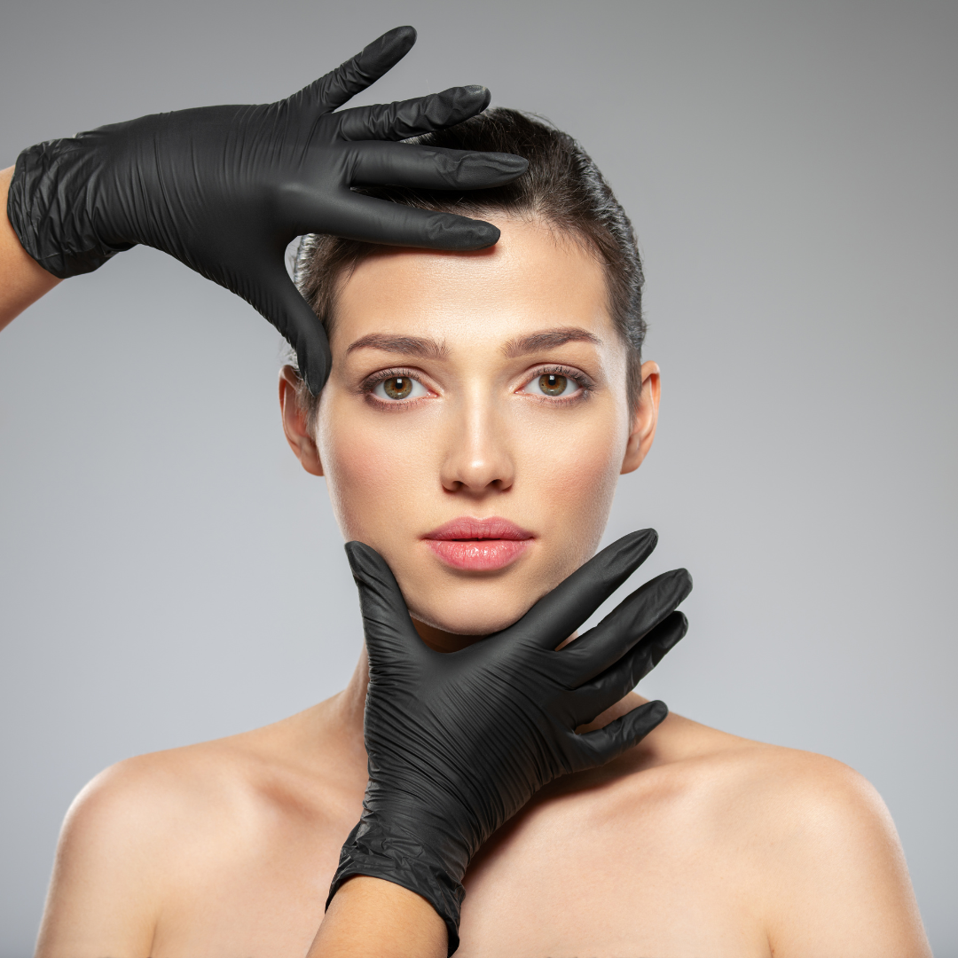 Eine Frau mit schwarzen Handschuhen bildet einen Rahmen um ihr Gesicht.