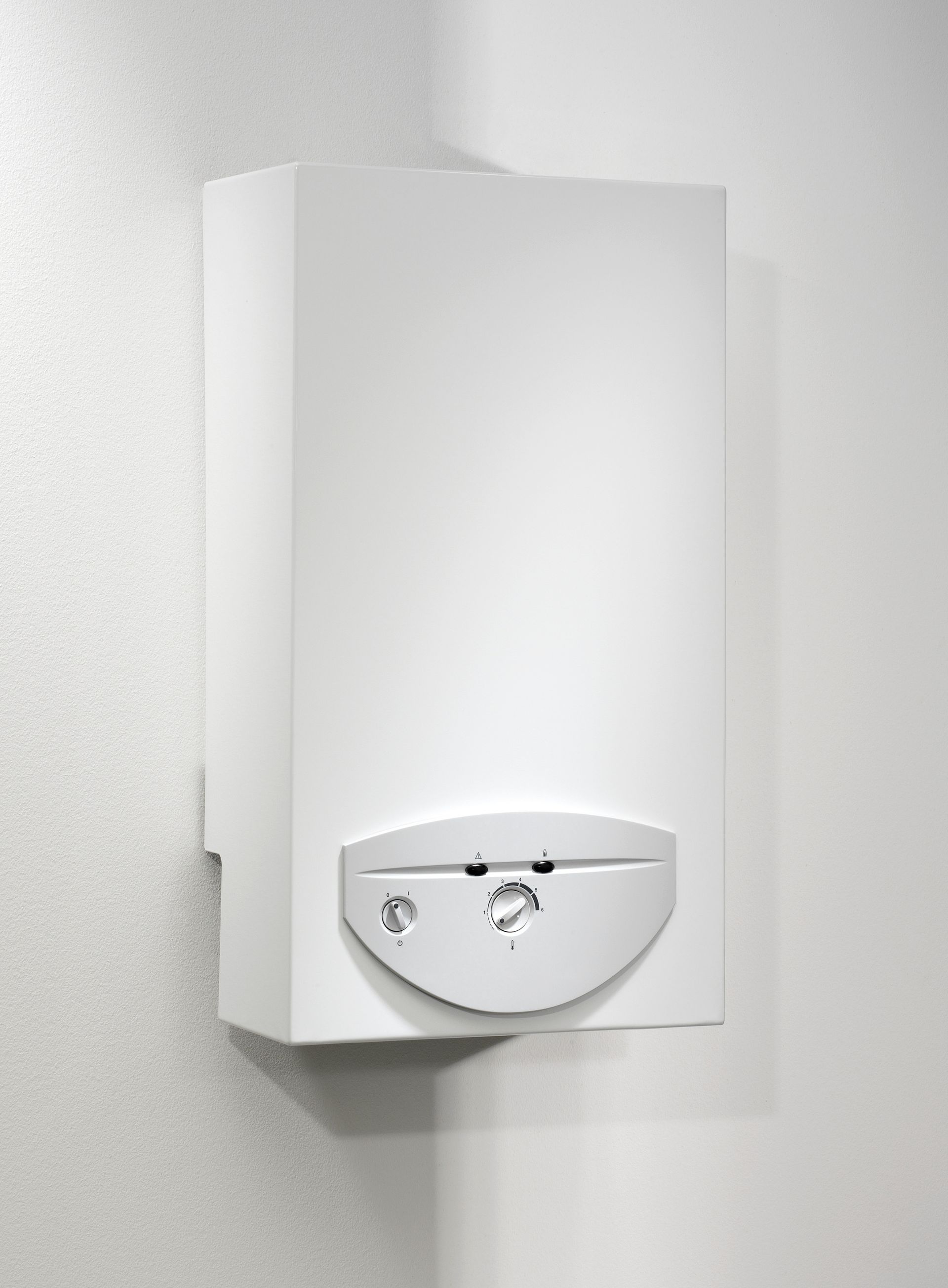 Une chaudière à gaz murale blanche avec un panneau de commande central, présentée sur un mur d'angle blanc uni.