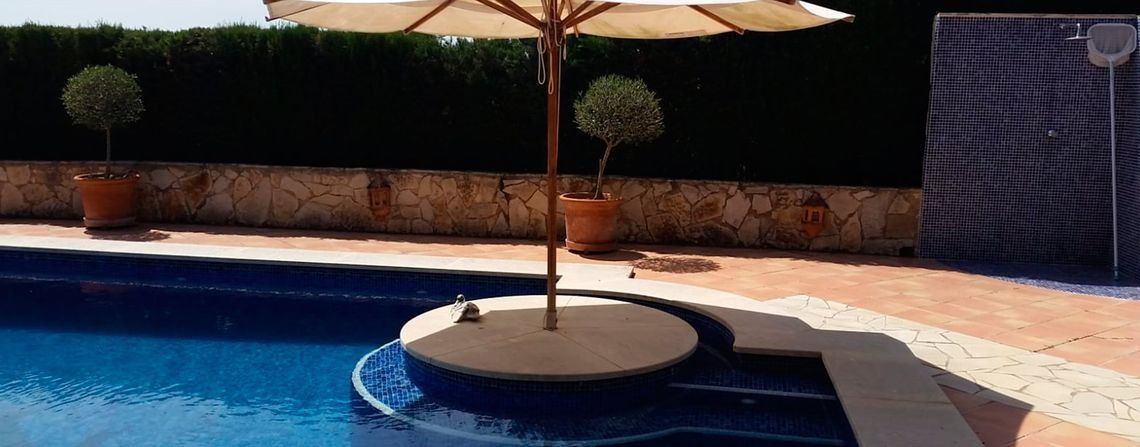 Una sombrilla está sentada en una pequeña isla en el medio de una piscina.