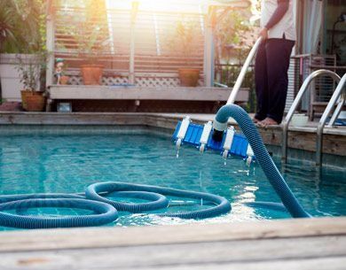 Un hombre está limpiando una piscina con una manguera.