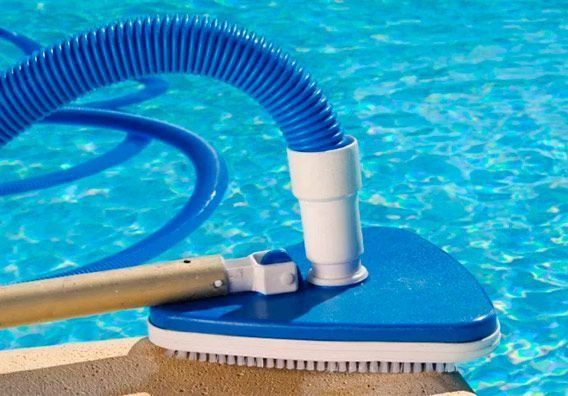 Una aspiradora está sentada en el borde de una piscina.